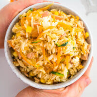 fried rice in a bowl with hands around it
