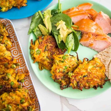 zucchini, carrot and pea fritters on a plate with salad