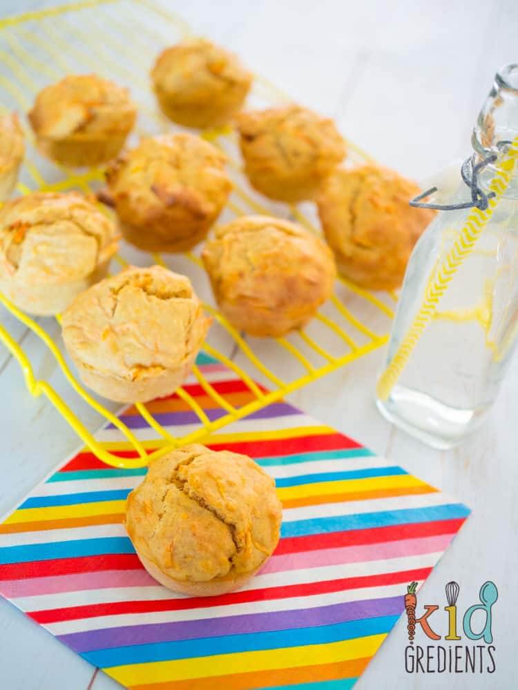 carrot and spice muffins, one muffin on a napkin ready for eating,  others cooling on a wire rack beside a bottle of water