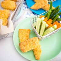 homemade fish fingers on a tray and on a plate with a basket of veggies