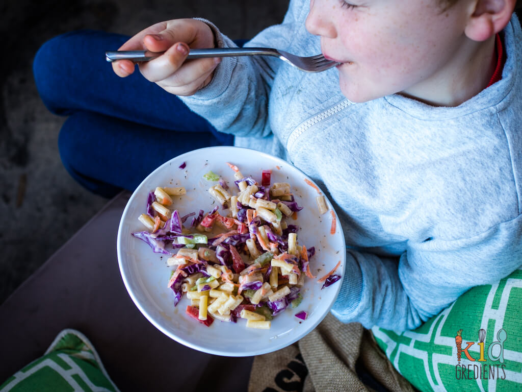 child eating the best ever rainbow pasta salad