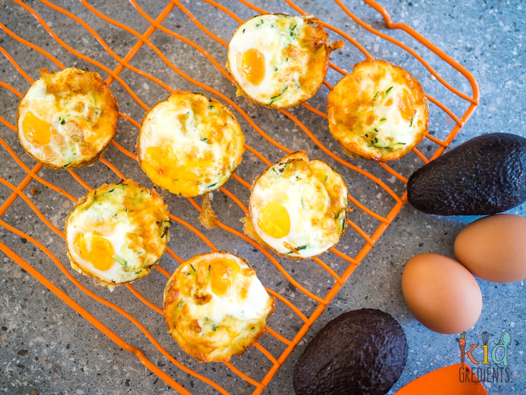 egg cups cooling on a wire rack, surrounded by eggs and avocadoes