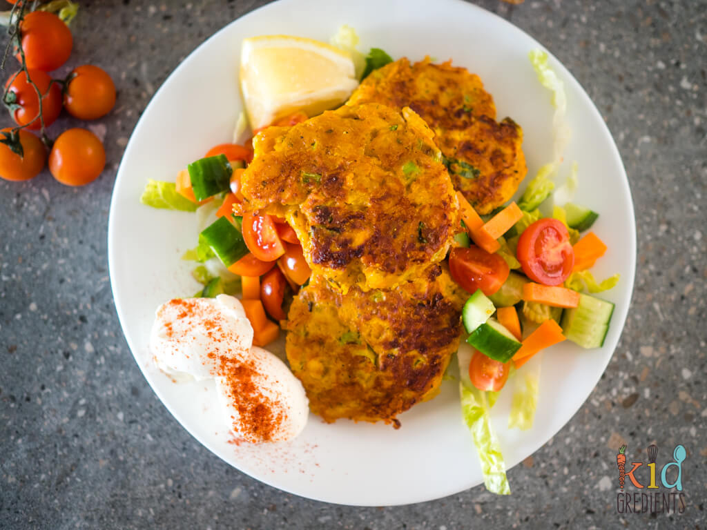 fritters served with quinelles of yoghurt topped with paprika and a chopped veggie salad of tomato, carrot and cucumber on a bed of lettuce