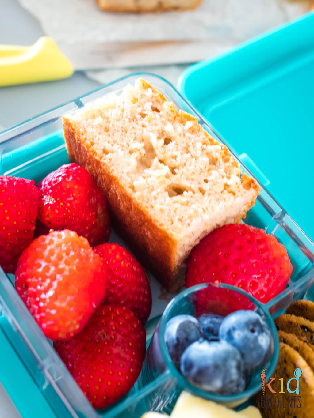 apple cake chopped in a lunchbox with strawberries and blueberries