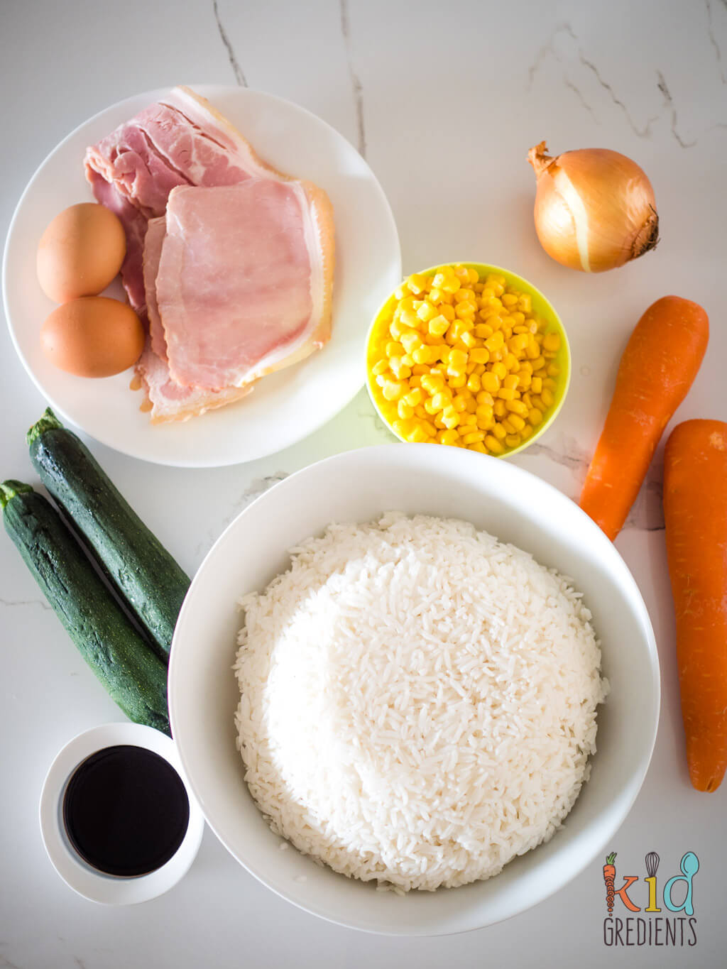 unprepped ingredients: rice, soy sauce, eggs, bacon, zucchini, carrots, corn and onion