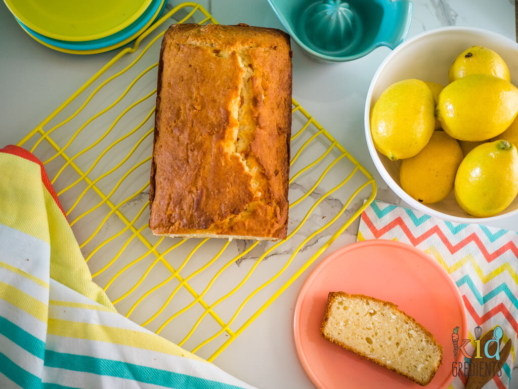 coconut and lemon yoghurt loaf on rack and a plate, with a bowl of lemons