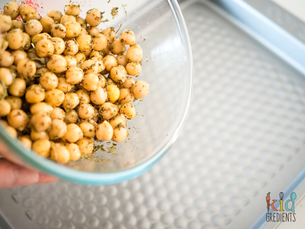 chickpeas pouring from the bowl to the tray for roasting