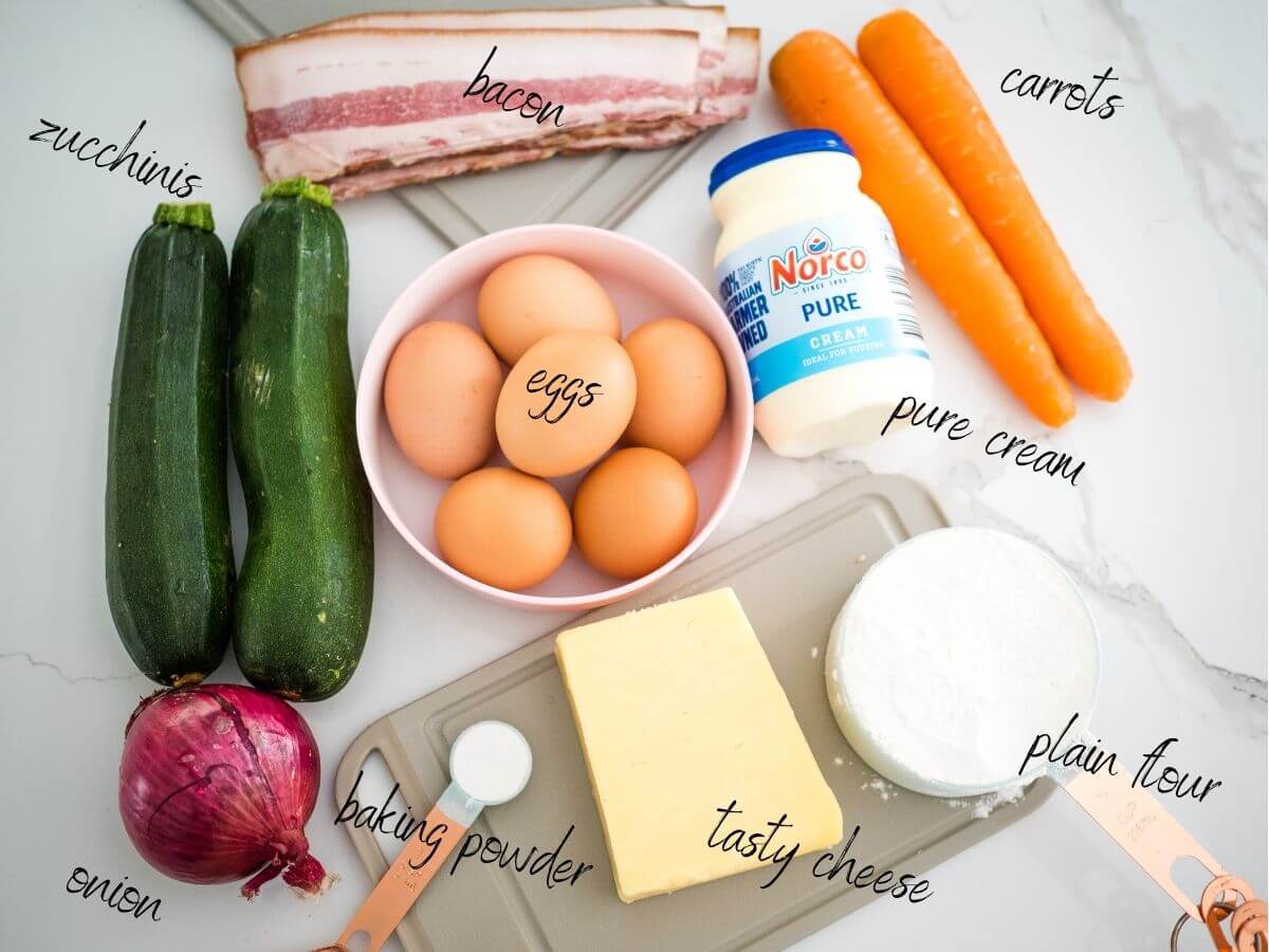 ingredients for easy zucchini slice: eggs, cream, flour, baking powder, zucchinis, carrots, bacon, onion and cheese