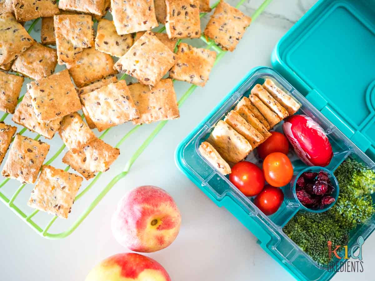 5 ingredient crackers on a cooling rack and in a lunchbox with tomatoes, cheese, cranberries and broccoli