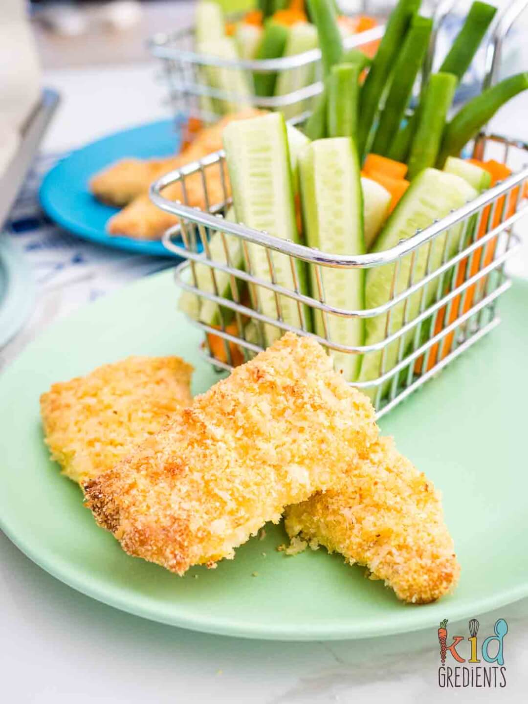 Homemade fish fingers on a green plate with veggies.