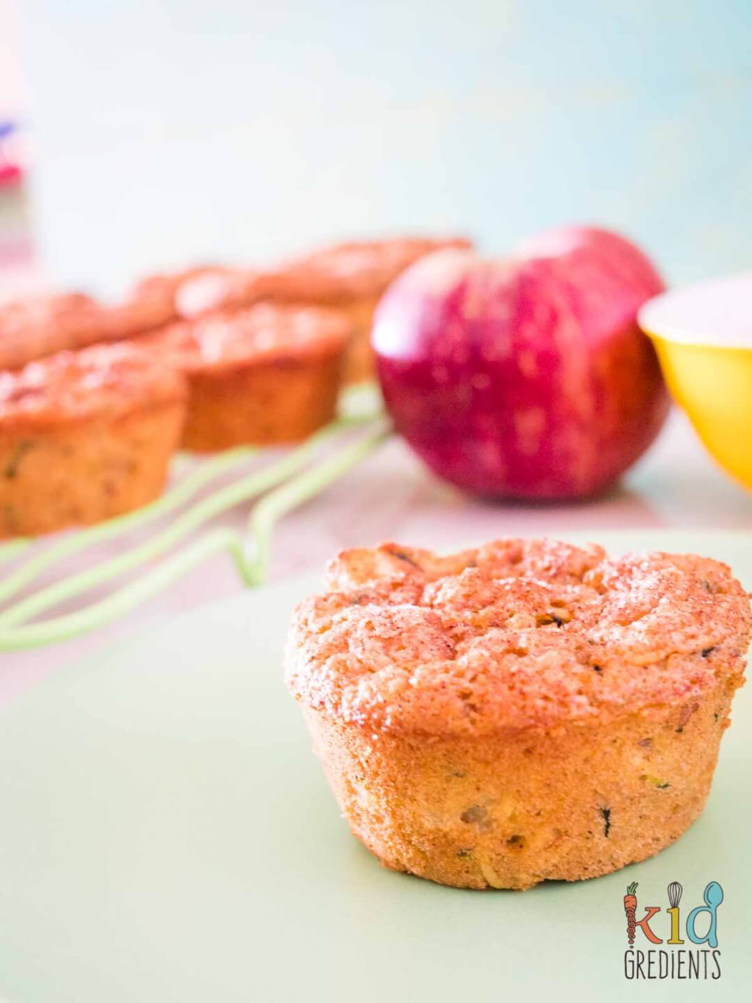 apple zucchini muffin with apples and muffins in the background