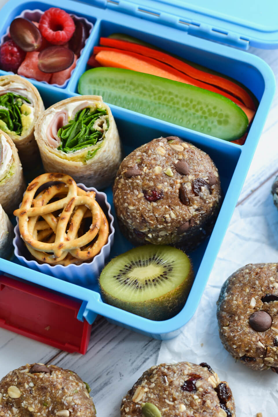 no bake trail mix cookies in a lunchbox with fruit and veggies and a wrap