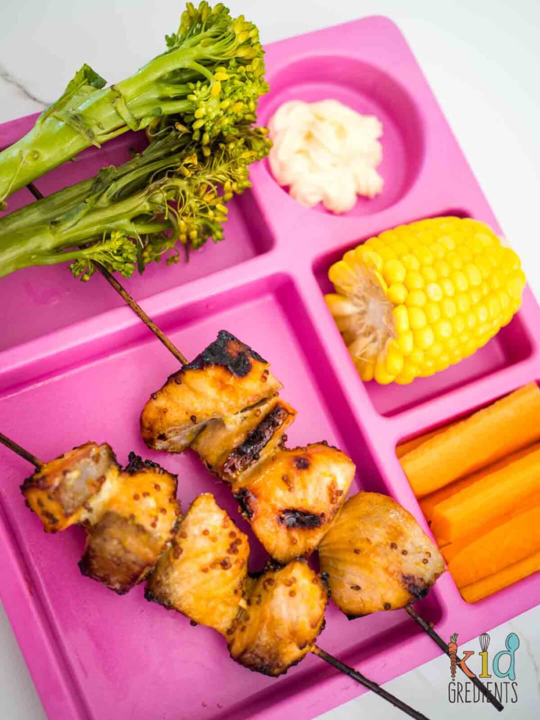 Salmon skewers with Orange Honey Mustard Glaze on a plate with broccoli, corn and carrots