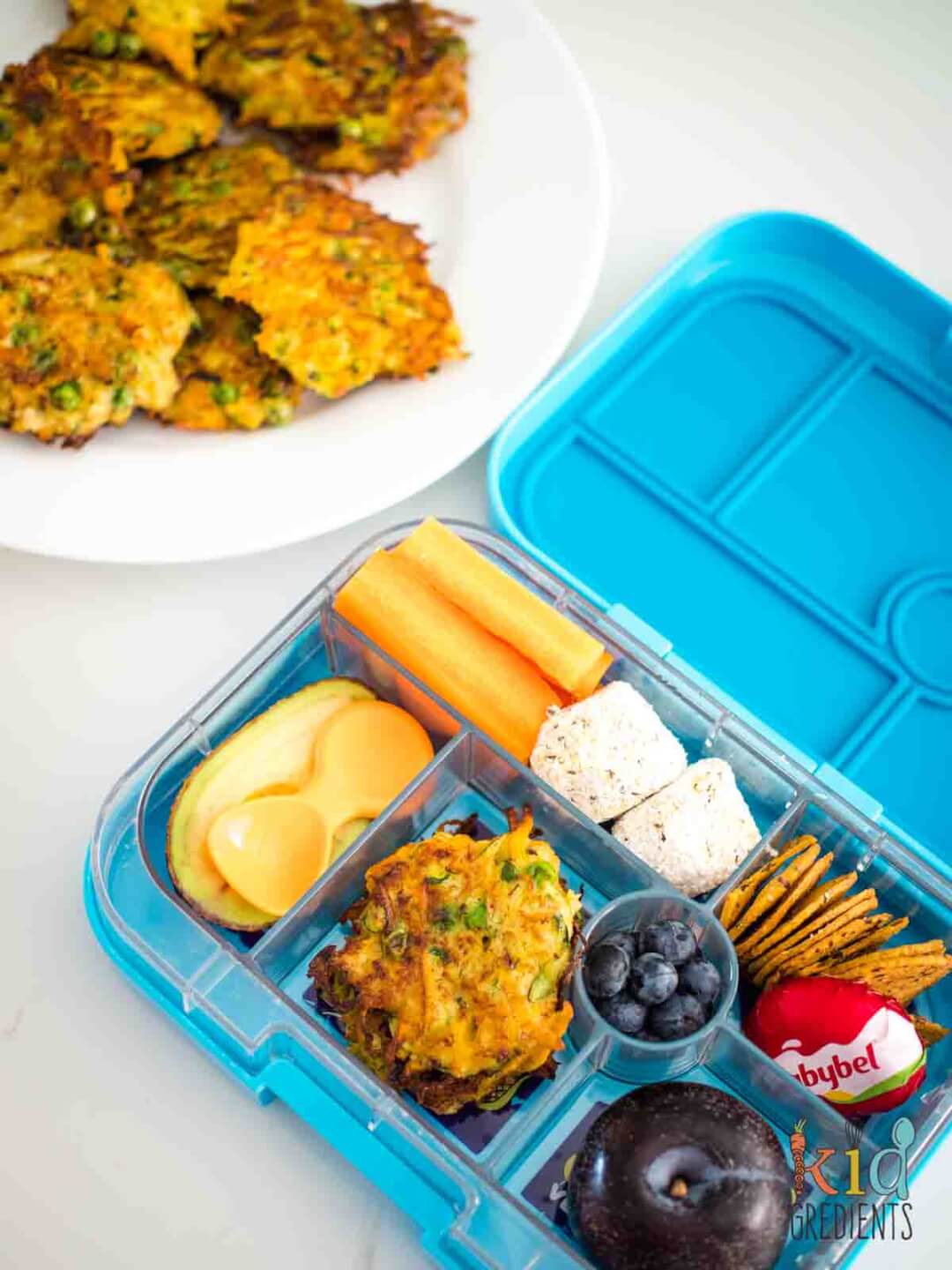 Zucchini, Carrot and Pea Fritters in the lunchbox with a plum, crackers, bliss balls, cheese and crackers and fruit and veggies
