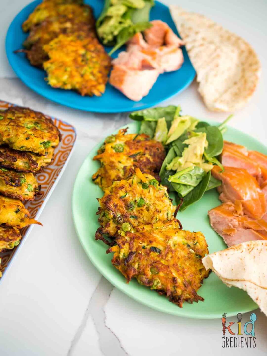 Zucchini, carrot and Pea fritters on a plate with salmon and salad