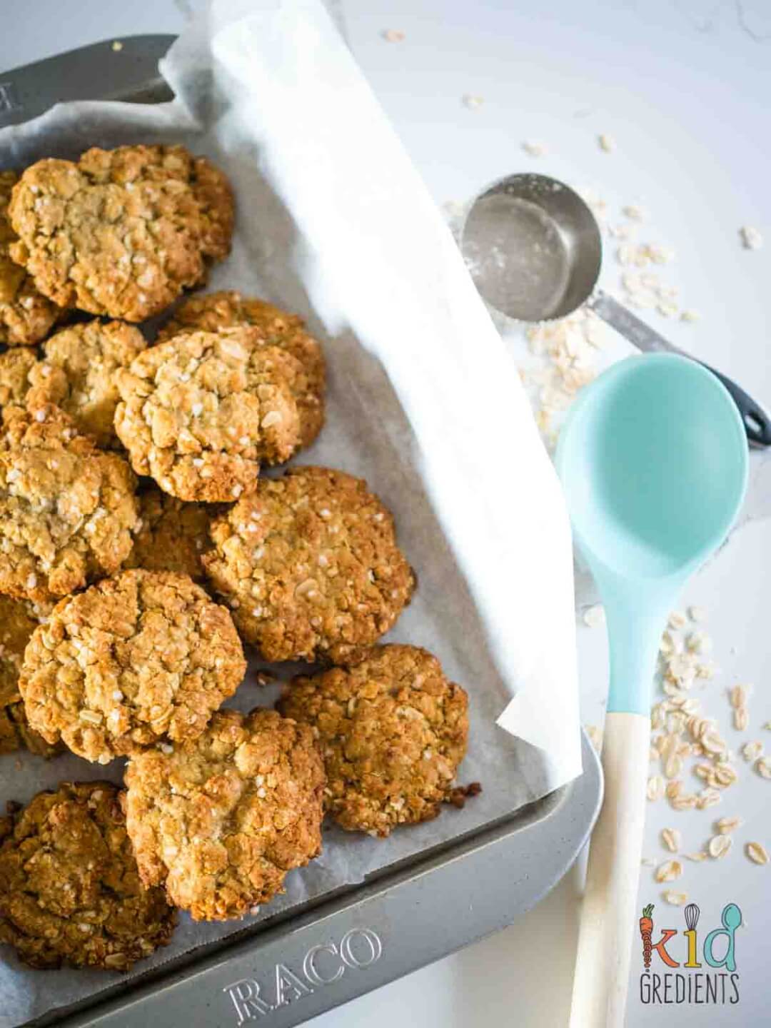 healthy anzac cookies on a baking tray with a spoon and spilled oats