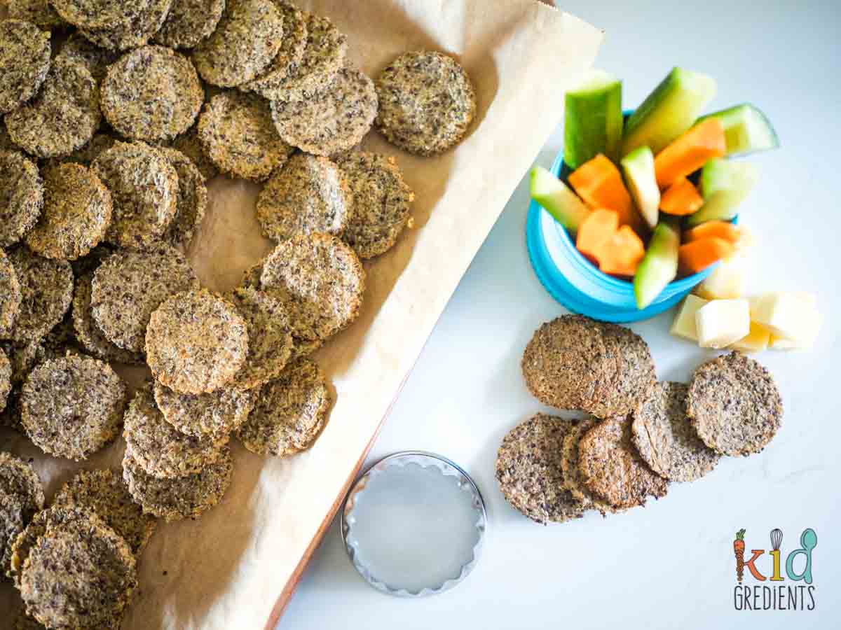 Easy Homemade Rice Crackers on a bench and on a tray, with fresh veggies