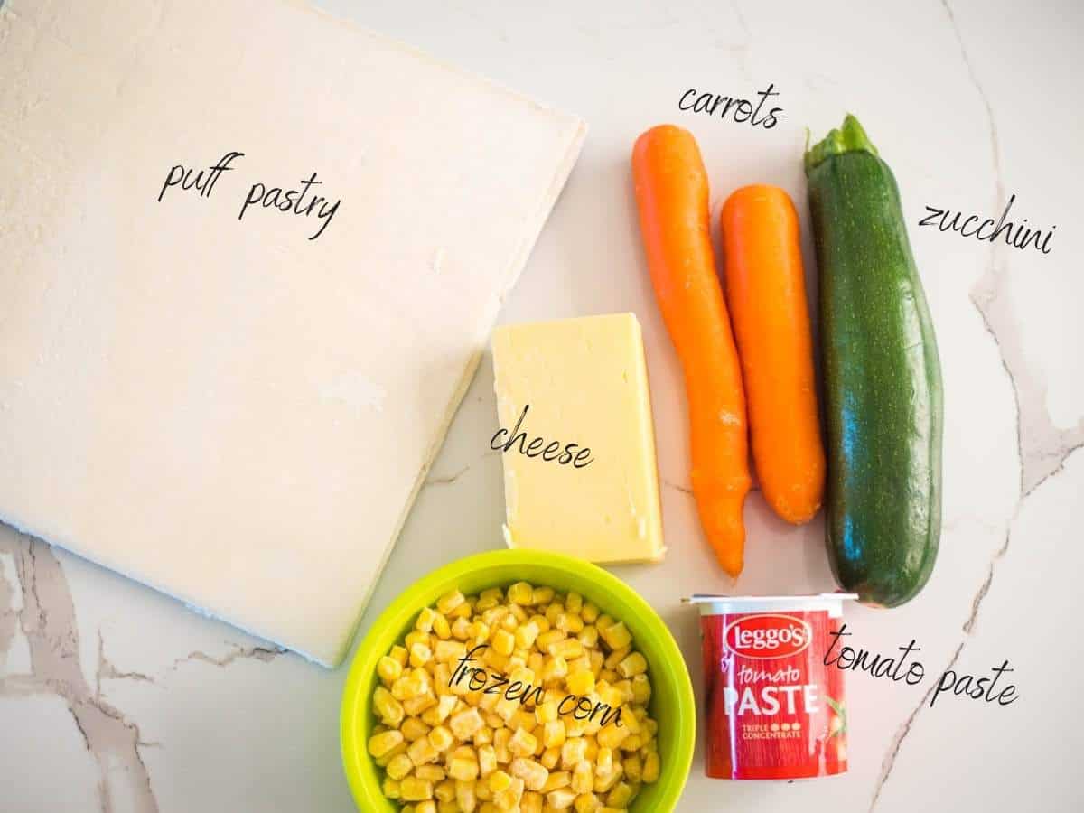 ingredients for three veg lunchbox scrolls: puff pastry, tomato paste, cheese, carrots, corn