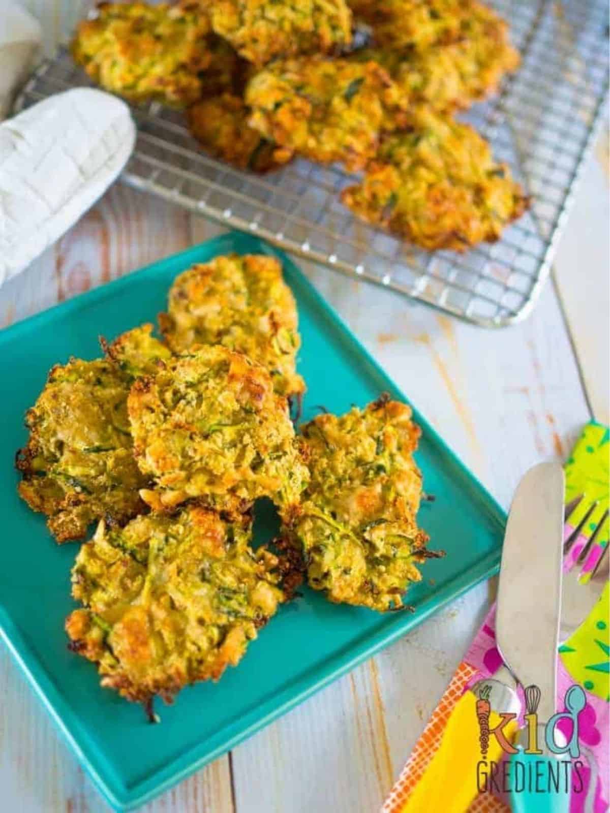 baked zucchini fritters on a plate and on a wire rack