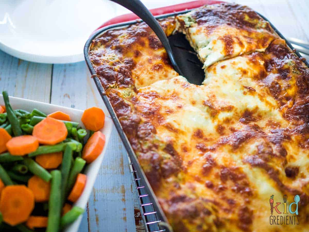 Lasagne in the tray next to a dish of fresh veggies