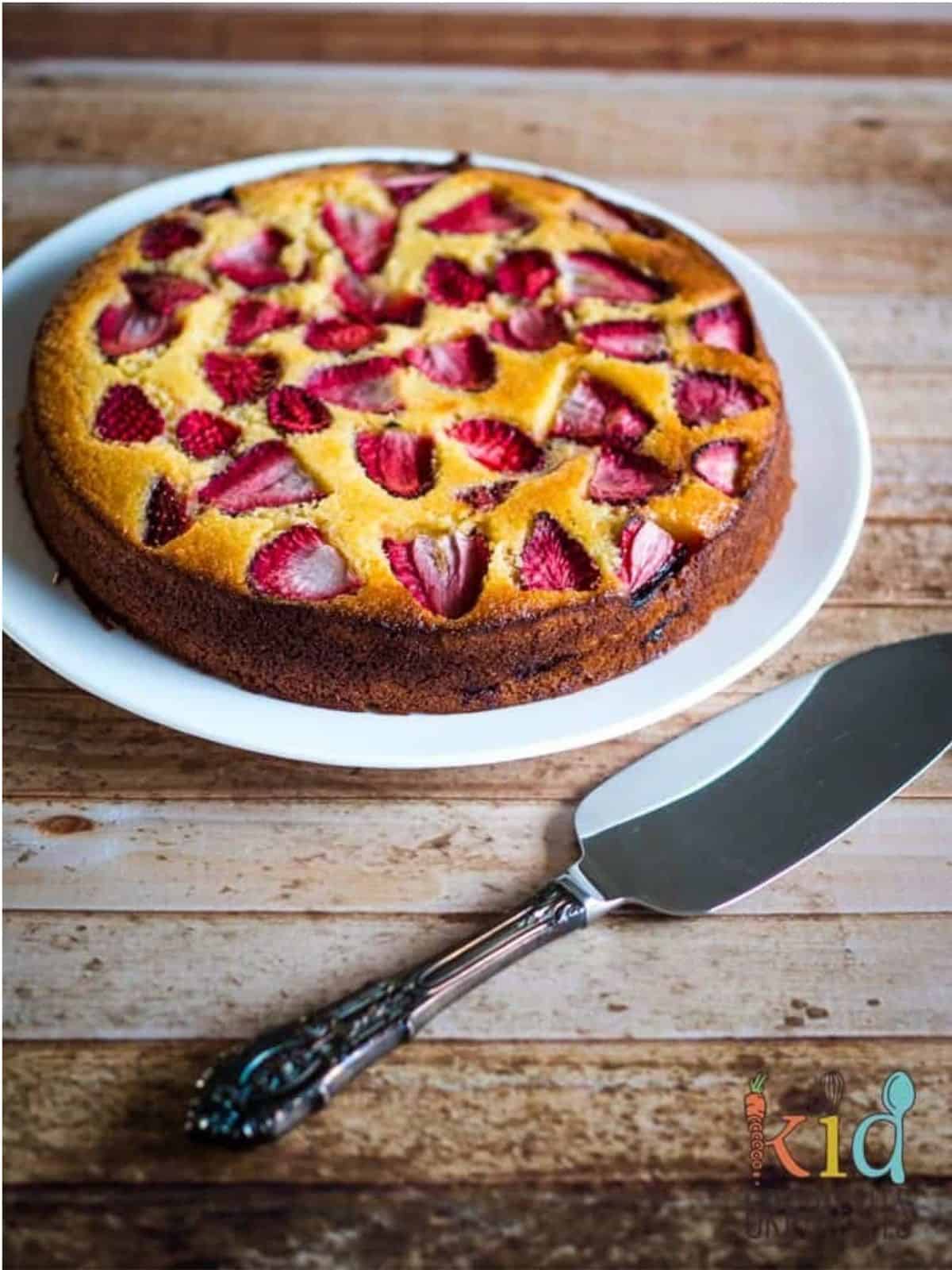 strawberry and lemon polenta cake on a plate with a serving utensil.