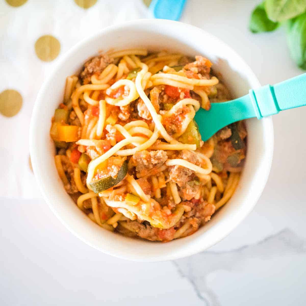 healthy turkey bolognese in a bowl with a teal fork