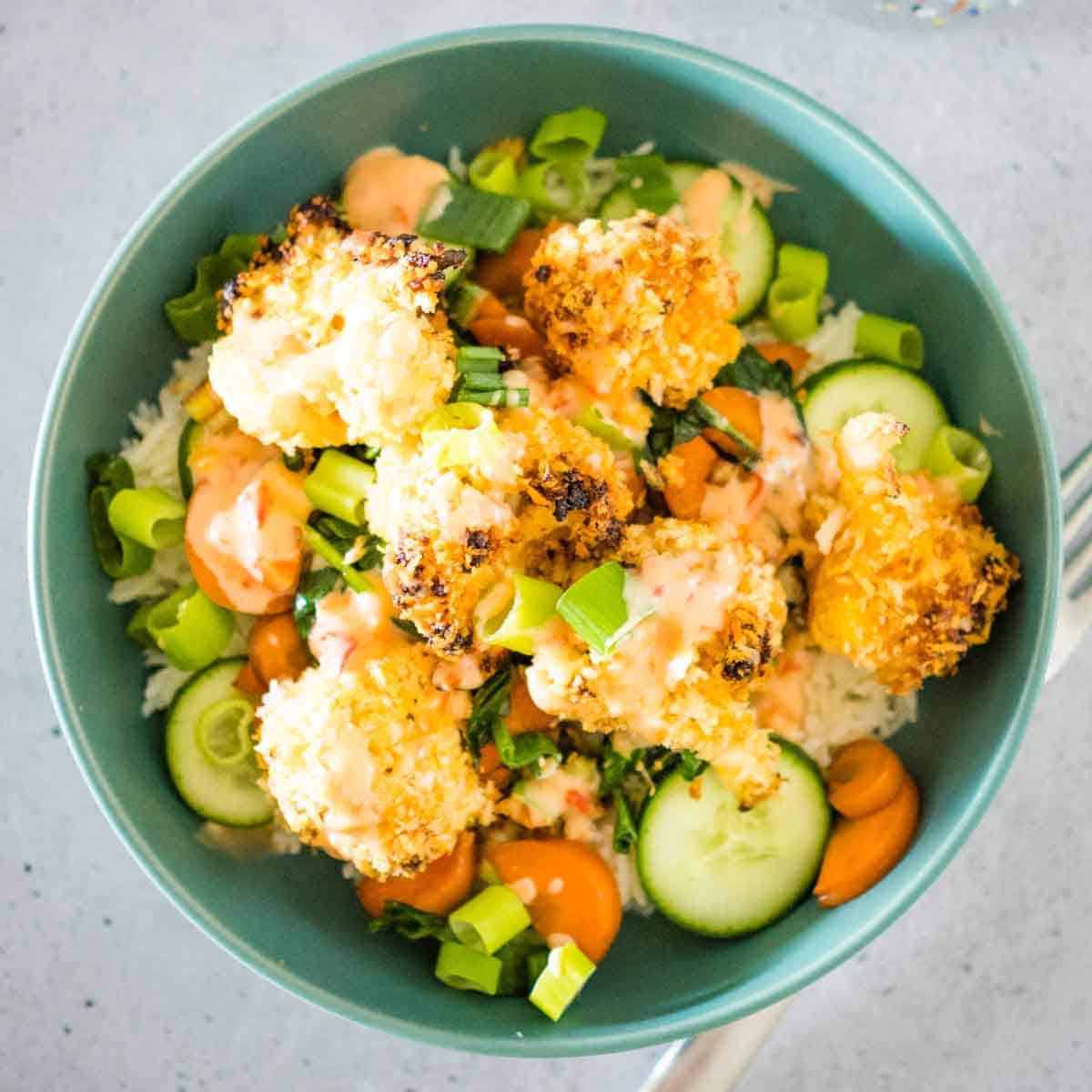 bang bang cauliflower in a bowl with tir fried veggies and rice