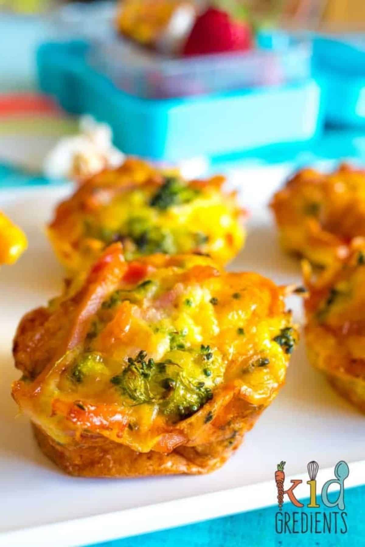 bacon and broccoli crustless quiches on a tray in front of a lunchboix