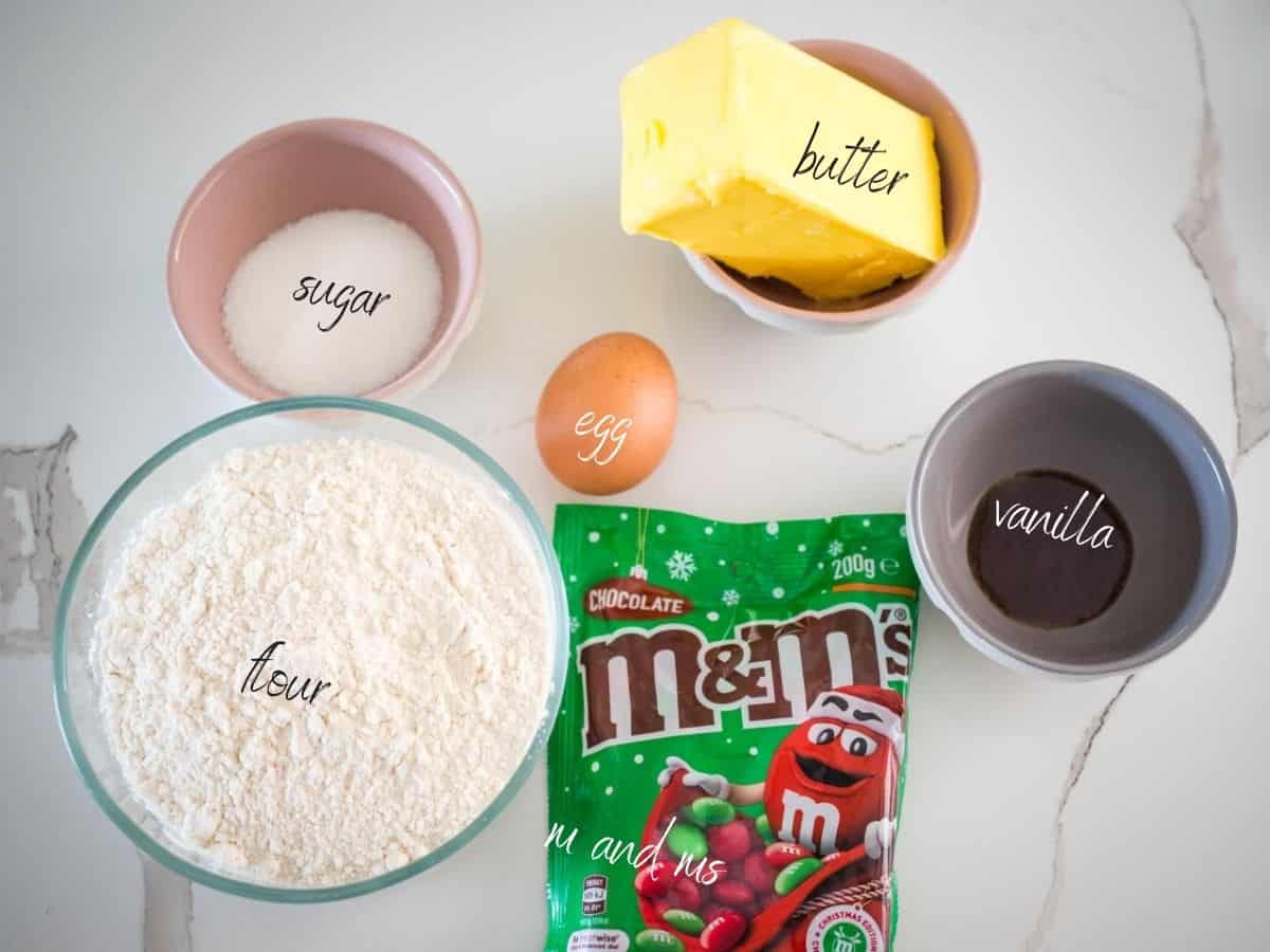 ingredients for christmas butter cookies. sugar, butter, vanilla, egg, flour and m and ms