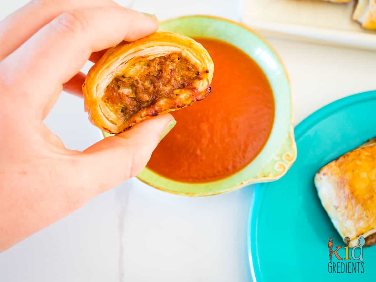Turkey Sausage Roll, being dipped in tomato sauce