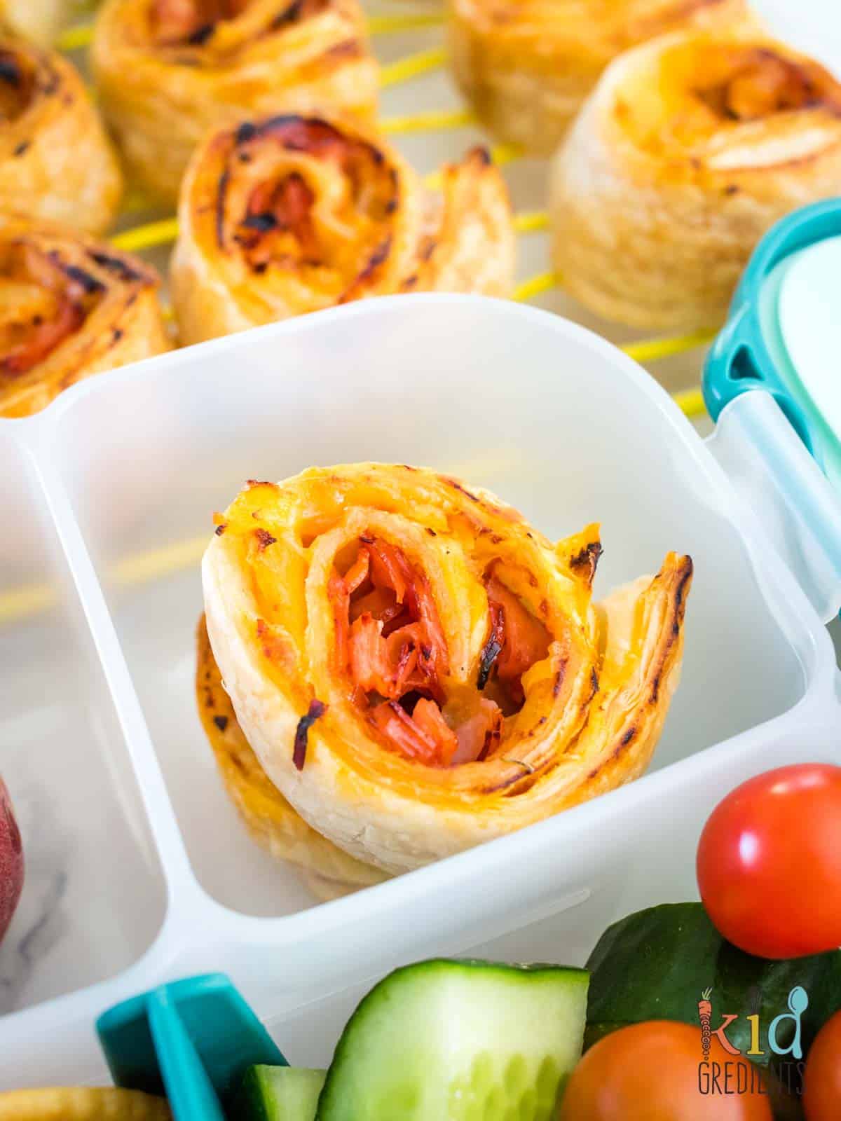Hawaiian pizza scrolls in the lunchbox and on a cooling. 