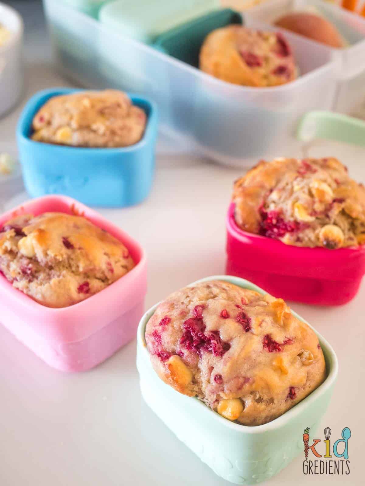 raspberry and white chocolate muffins in silicone snack cups with a bbox lunchbox in the background