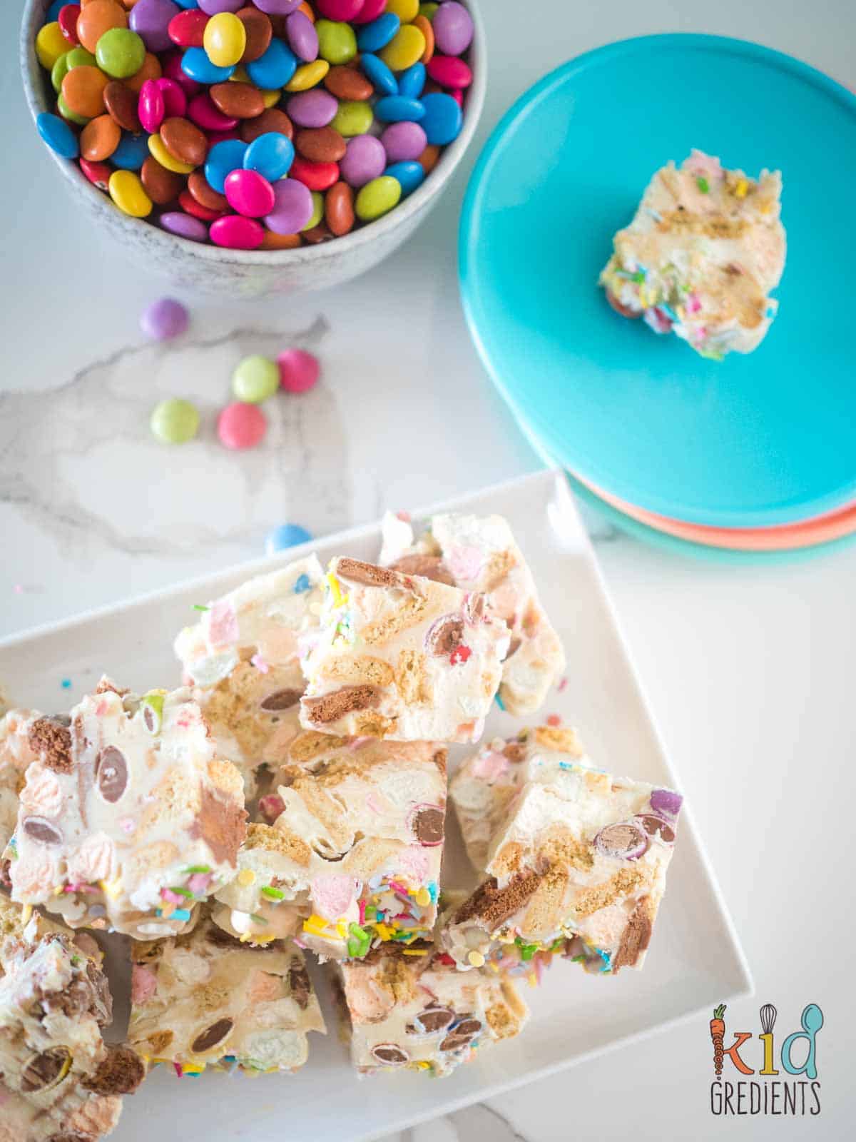 white chocolate rocky road on a platter chopped up, on a blue plate and smarties ina  bowl.