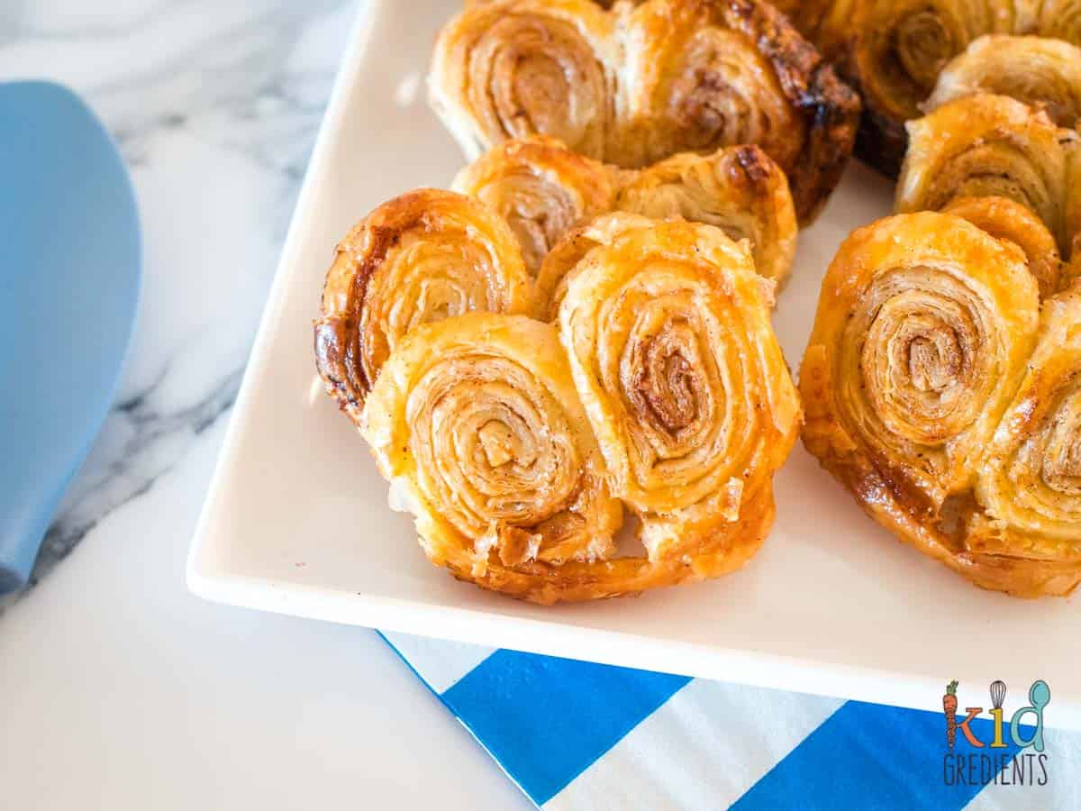 cinnamon sugar palmiers on a plate with a blue spoon and blue and white napkin