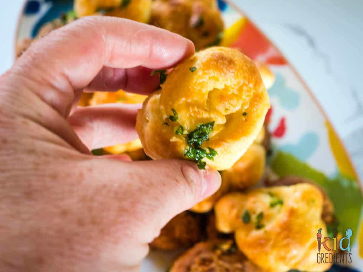 one garlic knot being held between two finger, fresh out of the airfryer