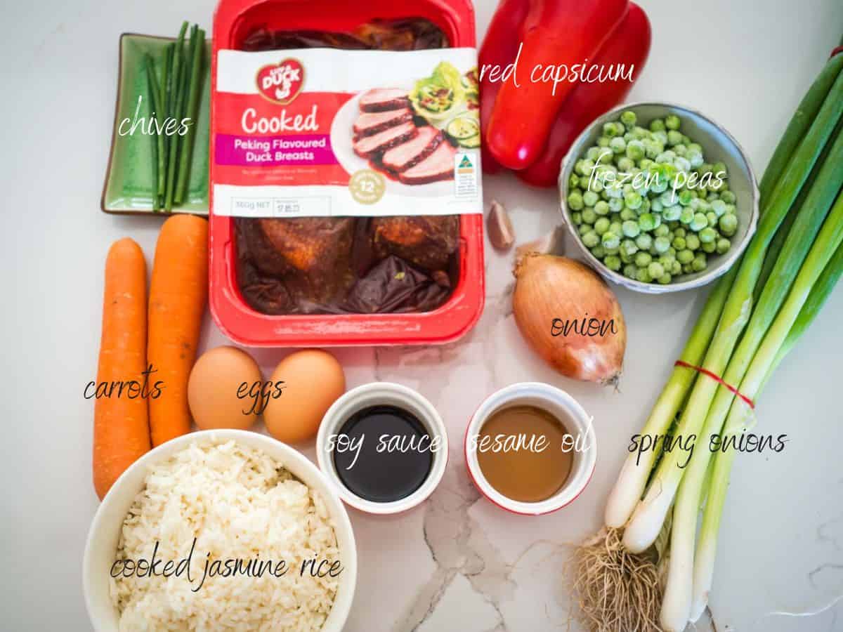 Ingredients for duck fried rice, duck, rice, chives, carrots, eggs, soy sauce, sesame oil, red capsicum, frozen peas, spring onions, onion, garlic